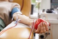 Close-up of patient with tubes in her arm squeezing the ball in her hand while donating the blood