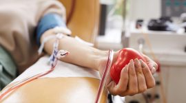 Close-up of patient with tubes in her arm squeezing the ball in her hand while donating the blood